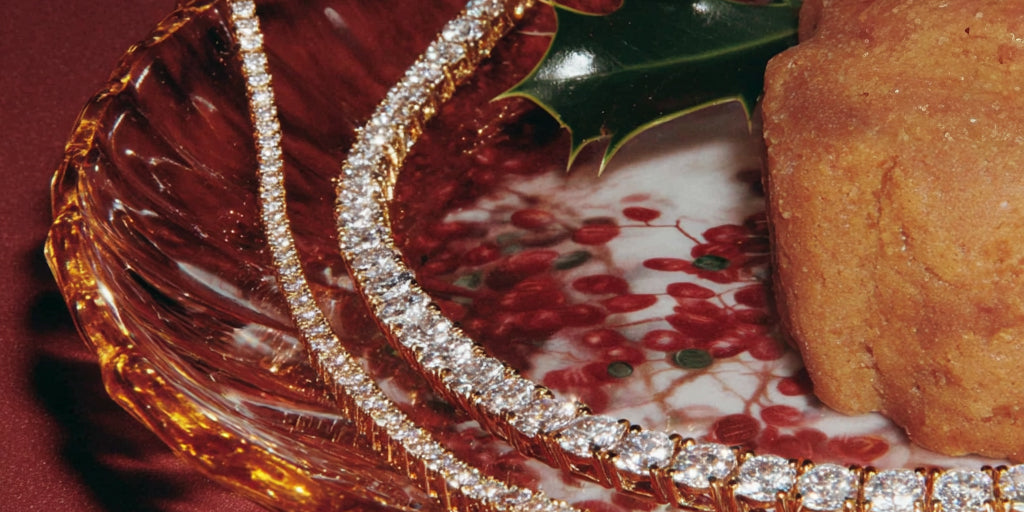 Diamond tennis bracelets on a christmas themed plate next to holly and cake