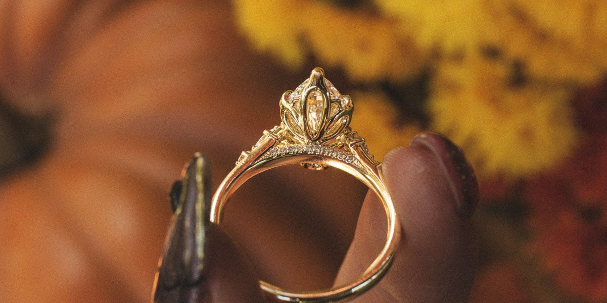 Made-to-order Jillian marquise lab grown diamond engagement ring in yellow gold, held in hand against fall flowers