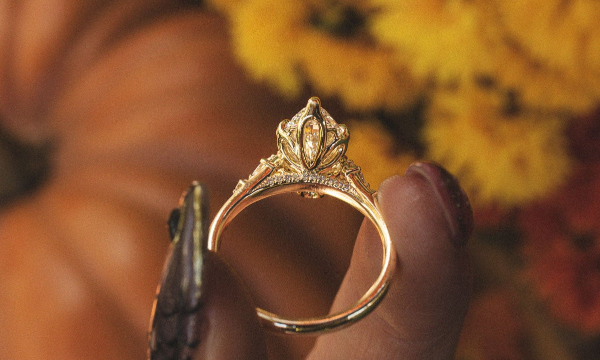 Made-to-order Jillian marquise lab grown diamond engagement ring in yellow gold, held in hand against fall flowers