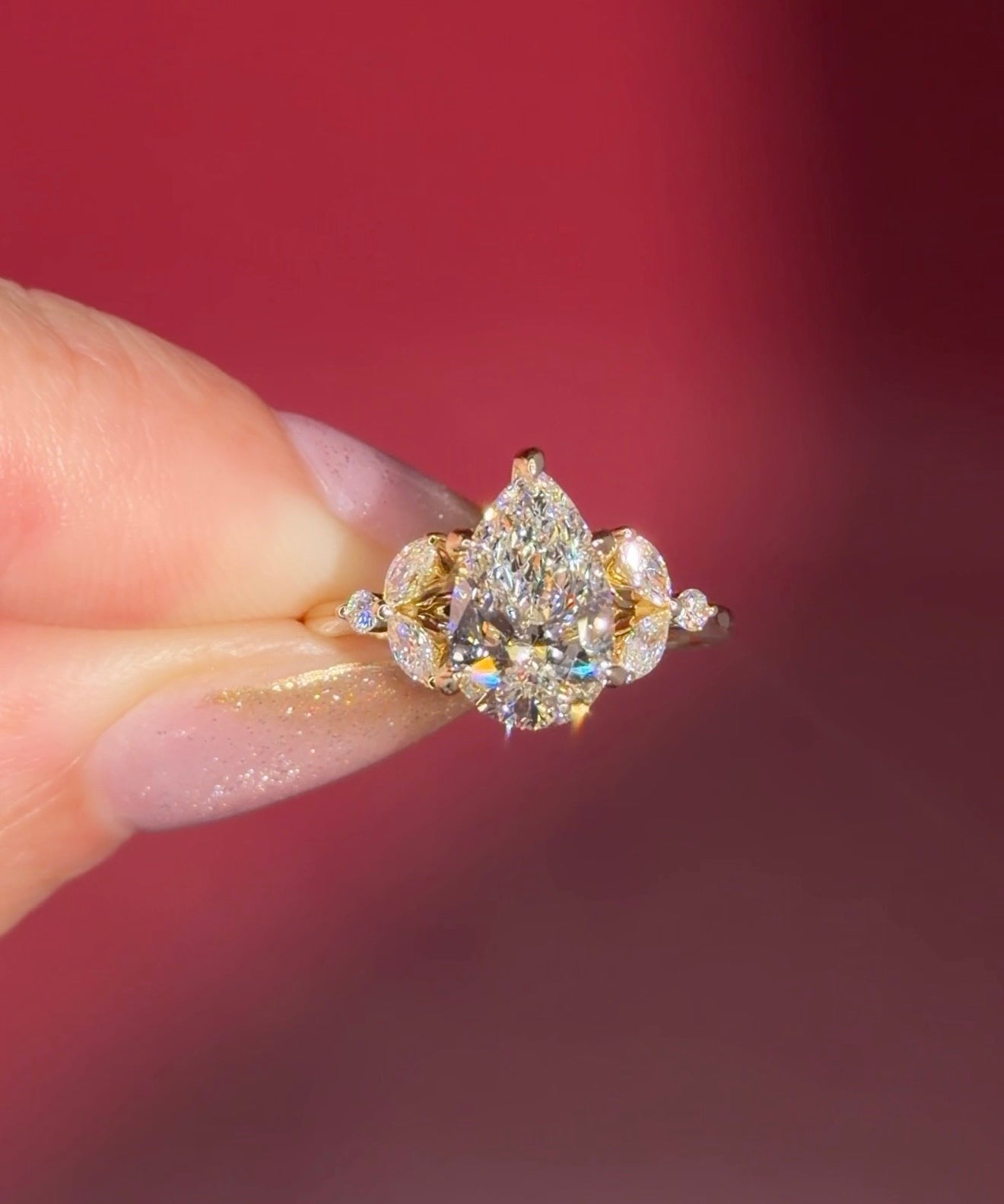 2.01ct F-VVS2 Pear Lab Diamond Sarah. The Sarah features a tapered high polish comfort fit band with a trio of diamonds. The trio features two marquises and one round diamond. The baskets are all lifted to fit a straight band flush against the body.