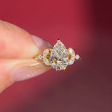 2.01ct F-VVS2 Pear Lab Diamond Sarah. The Sarah features a tapered high polish comfort fit band with a trio of diamonds. The trio features two marquises and one round diamond. The baskets are all lifted to fit a straight band flush against the body.