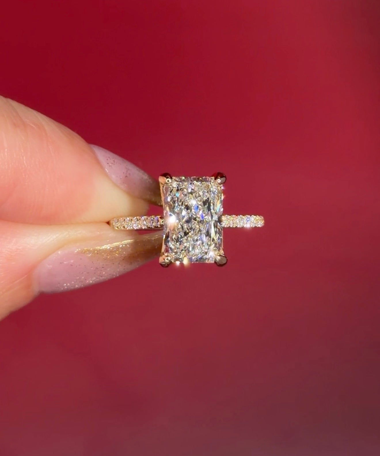 3.07ct F-VVS2 Radiant Lab Diamond Isabela. The Isabela is a cathedral style body with the key features being the pavé diamond lotus petal prongs and diamond bridge. This specific isabela is made with pavé side diamonds and is solid 14k yellow gold.
