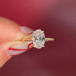 Oval solitaire with hidden halo and diamond bridge in yellow gold