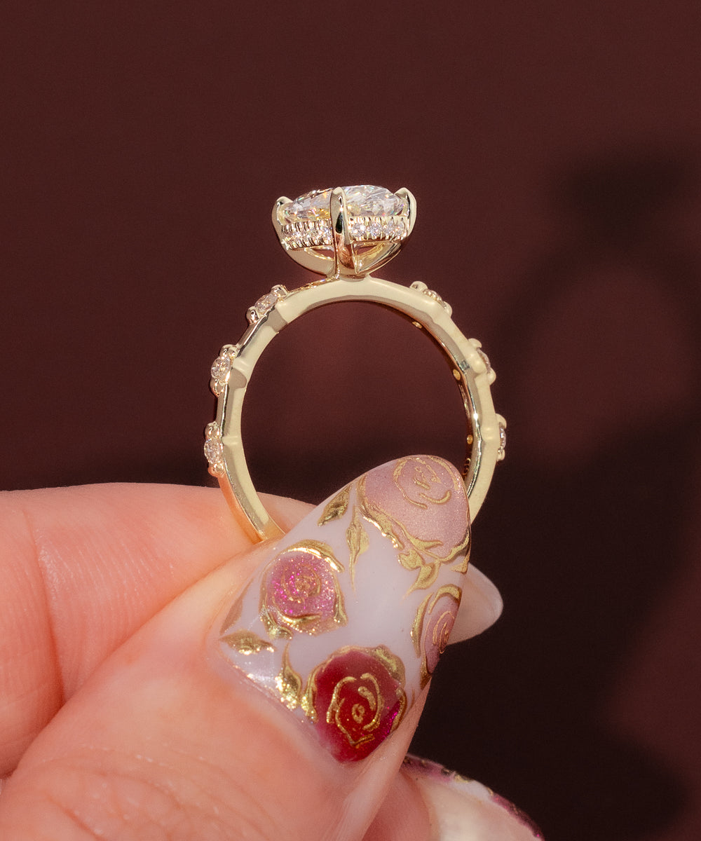 Profile view of oval engagement ring with hidden halo and elevated setting in yellow gold