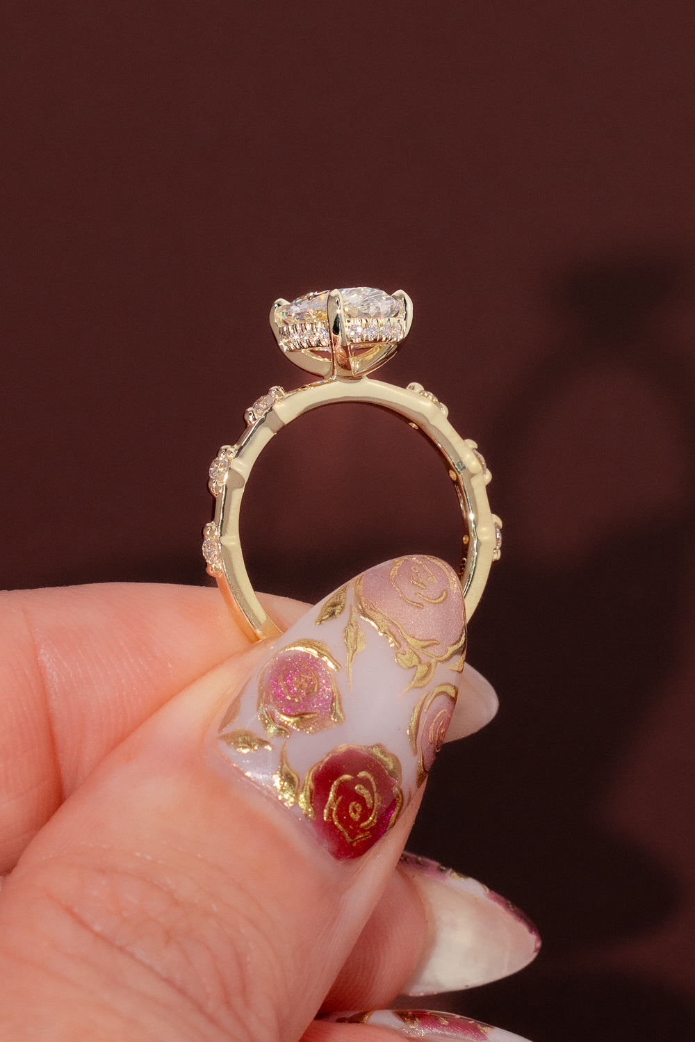 Profile view of oval engagement ring with hidden halo and elevated setting in yellow gold