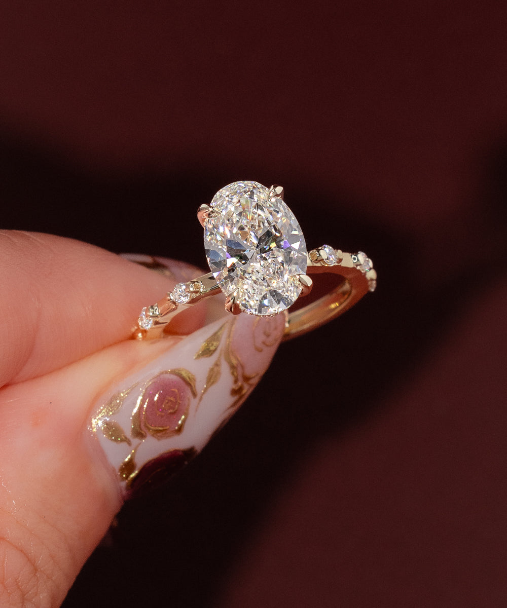 Yellow gold oval engagement ring with hidden halo and spaced diamond band, Daisy design