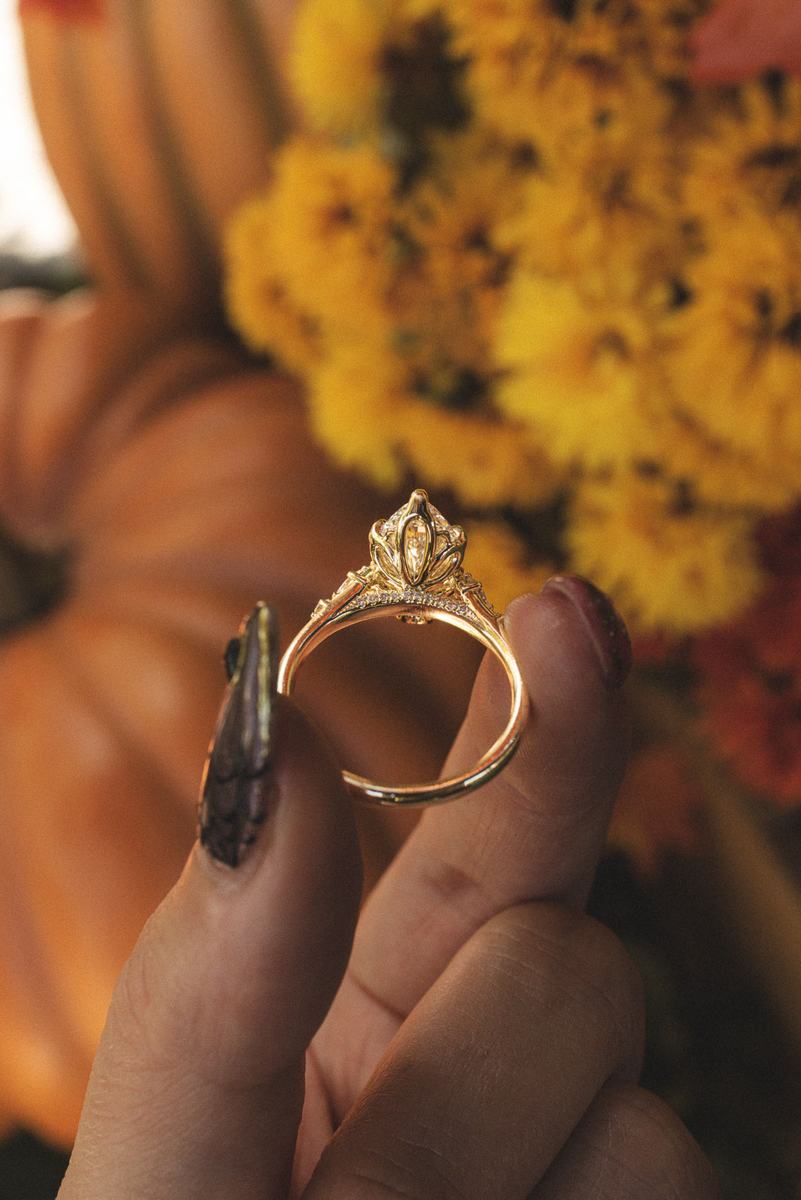 Jillian marquise lab grown diamond engagement ring in yellow gold with petal prongs, held against fall flowers