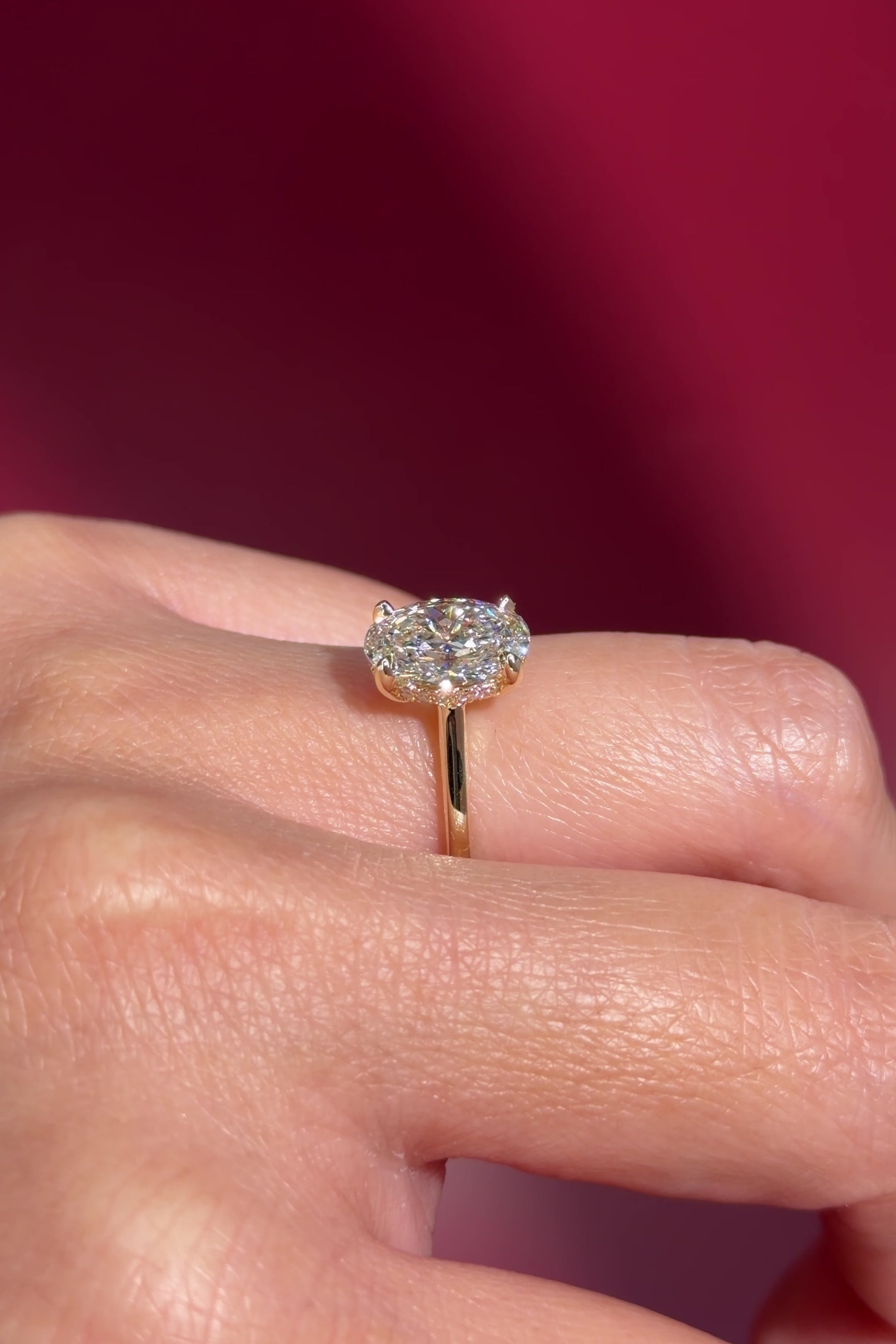 oval lab diamond yellow gold high polish engagement ring with cathedral and hidden halo on hand