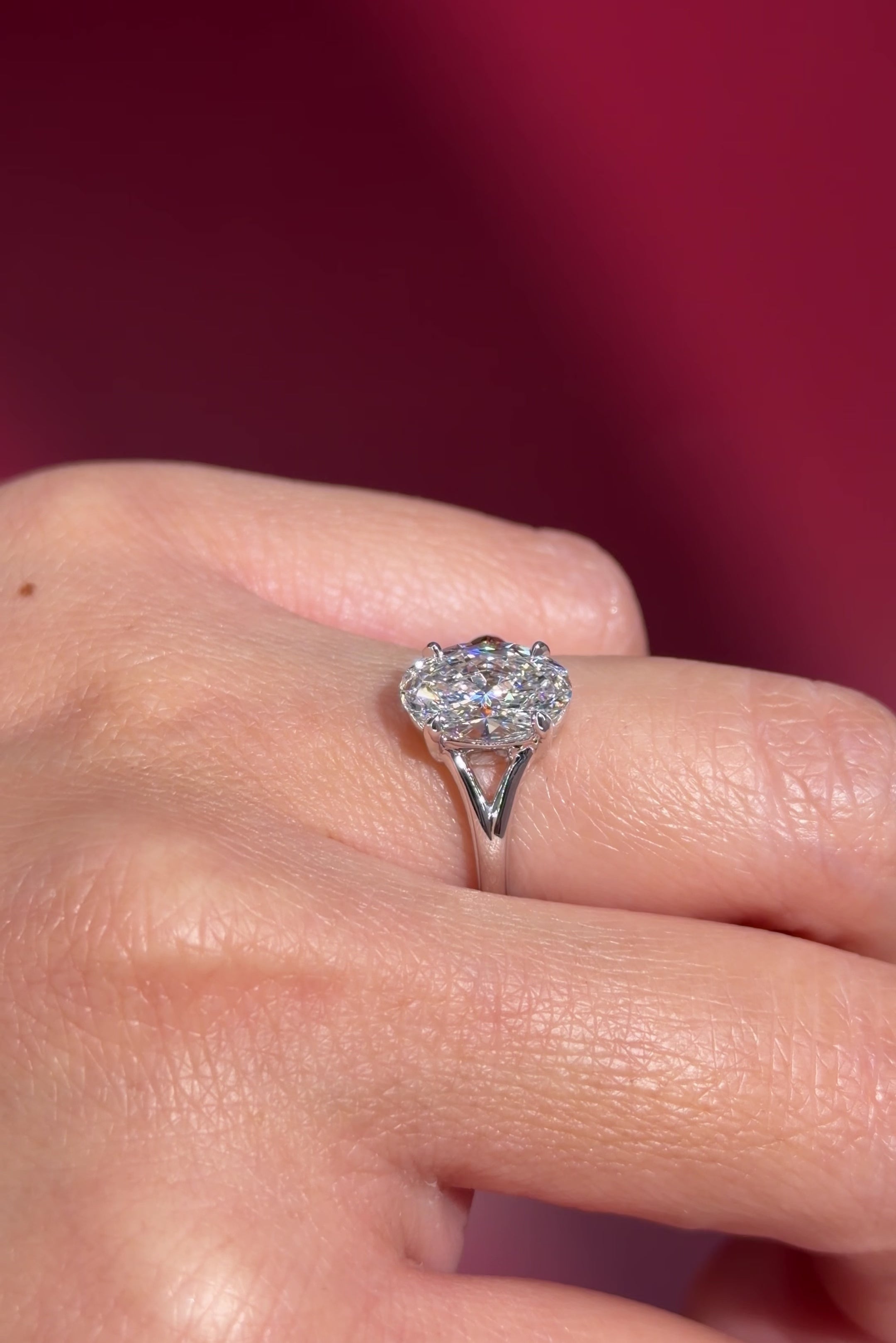 oval lab diamond white gold solitaire split shank engagement ring on hand