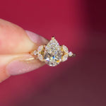 2.01ct F-VVS2 Pear Lab Diamond Sarah. The Sarah features a tapered high polish comfort fit band with a trio of diamonds. The trio features two marquises and one round diamond. The baskets are all lifted to fit a straight band flush against the body.