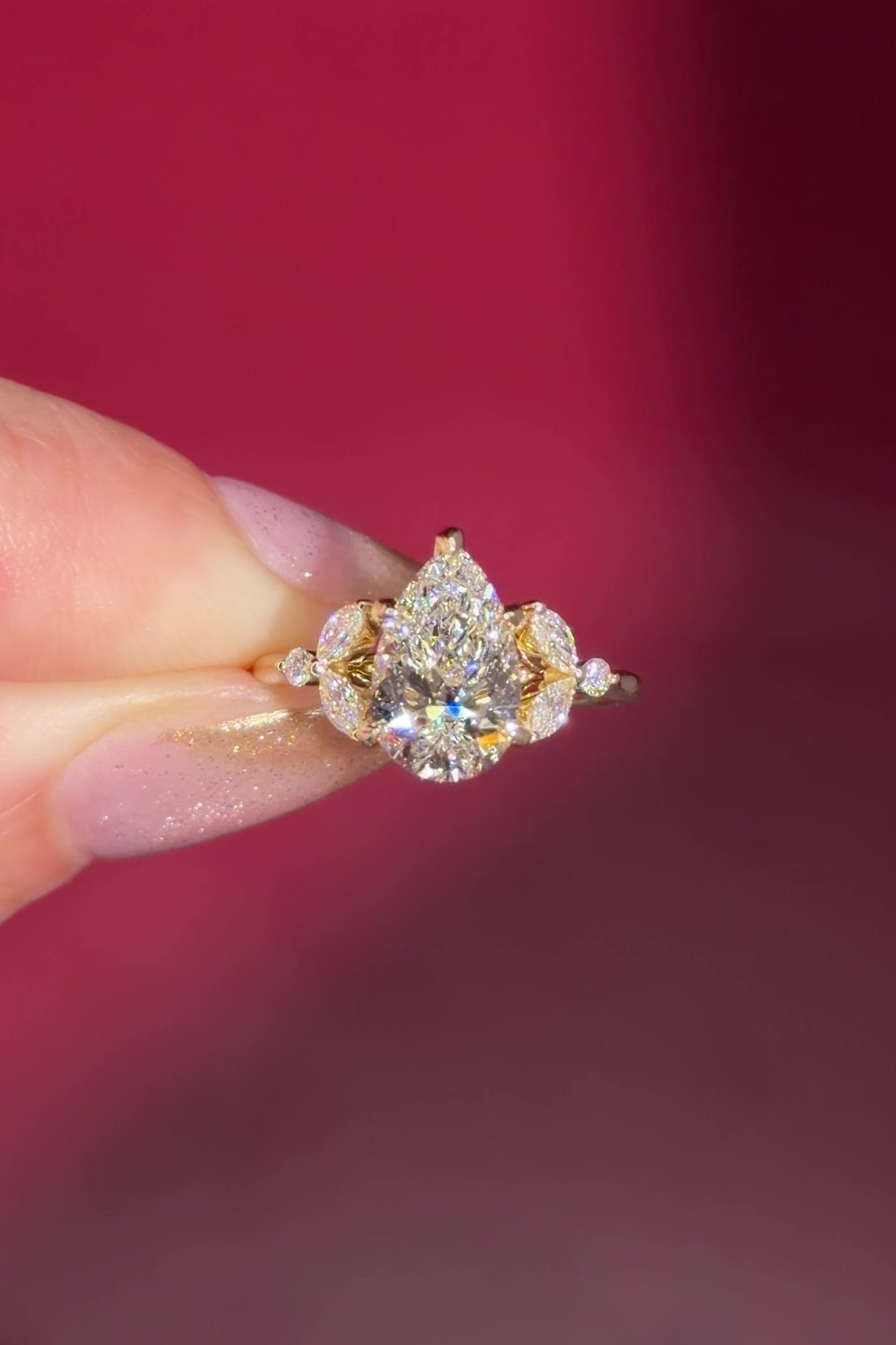 2.01ct F-VVS2 Pear Lab Diamond Sarah. The Sarah features a tapered high polish comfort fit band with a trio of diamonds. The trio features two marquises and one round diamond. The baskets are all lifted to fit a straight band flush against the body.