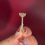 Round Solitaire Engagement Ring with Pavé Side Diamonds in yellow Gold with Petal Prongs being held by hand