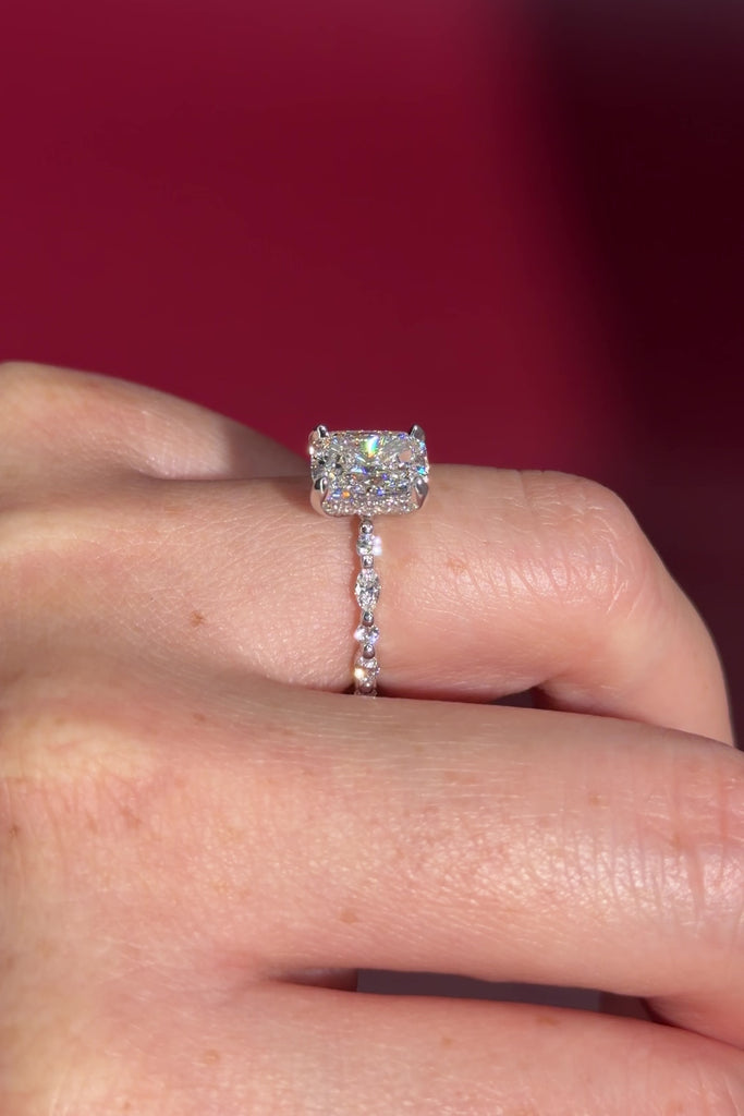 The Rei is a traditional style engagement ring featuring a hidden halo set between the prongs, adding subtle sparkle beneath the center stone.

The standout detail of this design is the floating marquise and round side diamonds, each held by a single prong. This setting allows each side diamond to be fully visible from every angle, creating a light, airy, and elegant look.

Because of this construction, Rei is a more delicate and high maintenance style, best suited for those who are mindful with daily wear 