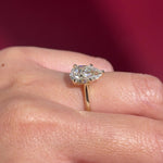 pear lab diamond solitaire engagement ring with cathedral and belt on hand