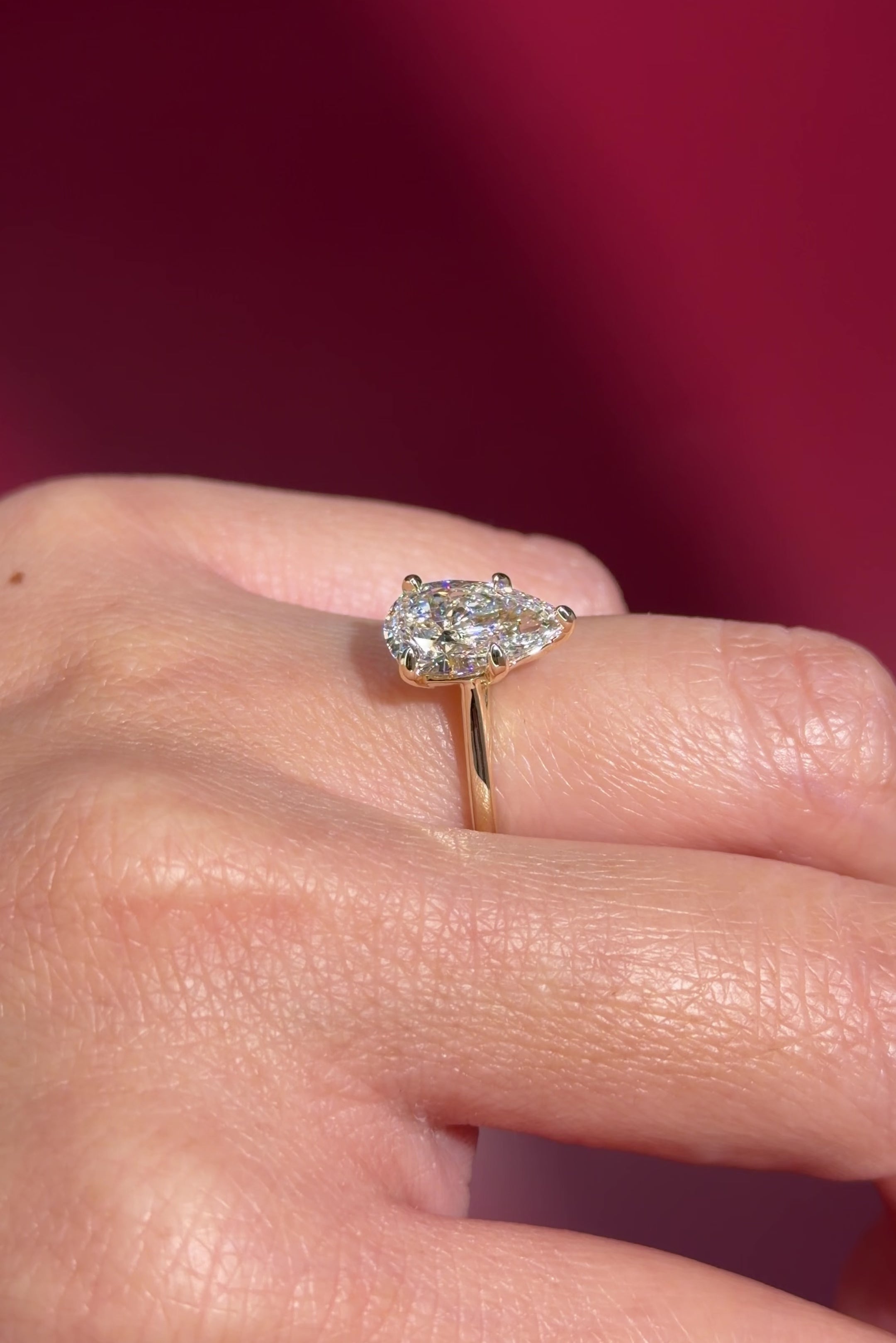 pear lab diamond solitaire engagement ring with cathedral and belt on hand