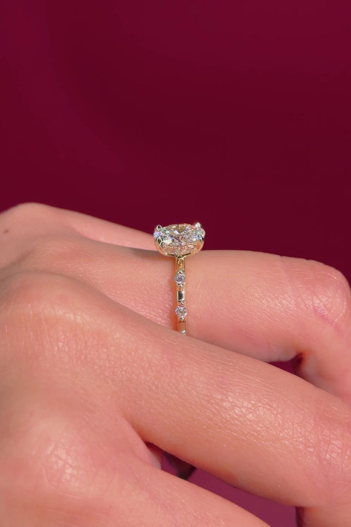 oval floating diamond spaced out band yellow gold engagement ring on hand