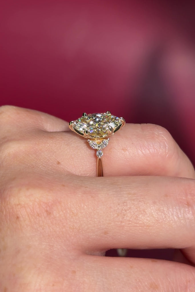 3.01ct F-VVS2 Marquise Lab Diamond Olivia. Three stone style engagement ring featuring two marquise and one round diamond at the bottom of the tro. The marquise act as diamond leaves holding the center stone. From the side profile the Olivia features a diamond bridge and diamond petal prongs.