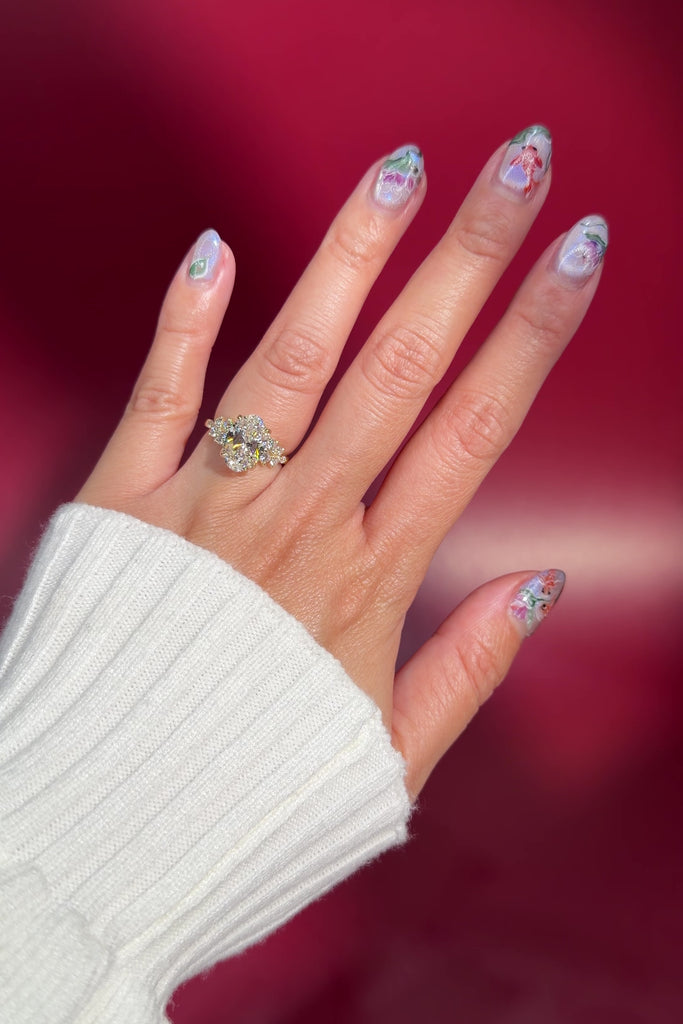 oval lab diamond side stones cluster style engagement ring setting yellow gold with petal prong basket on hand