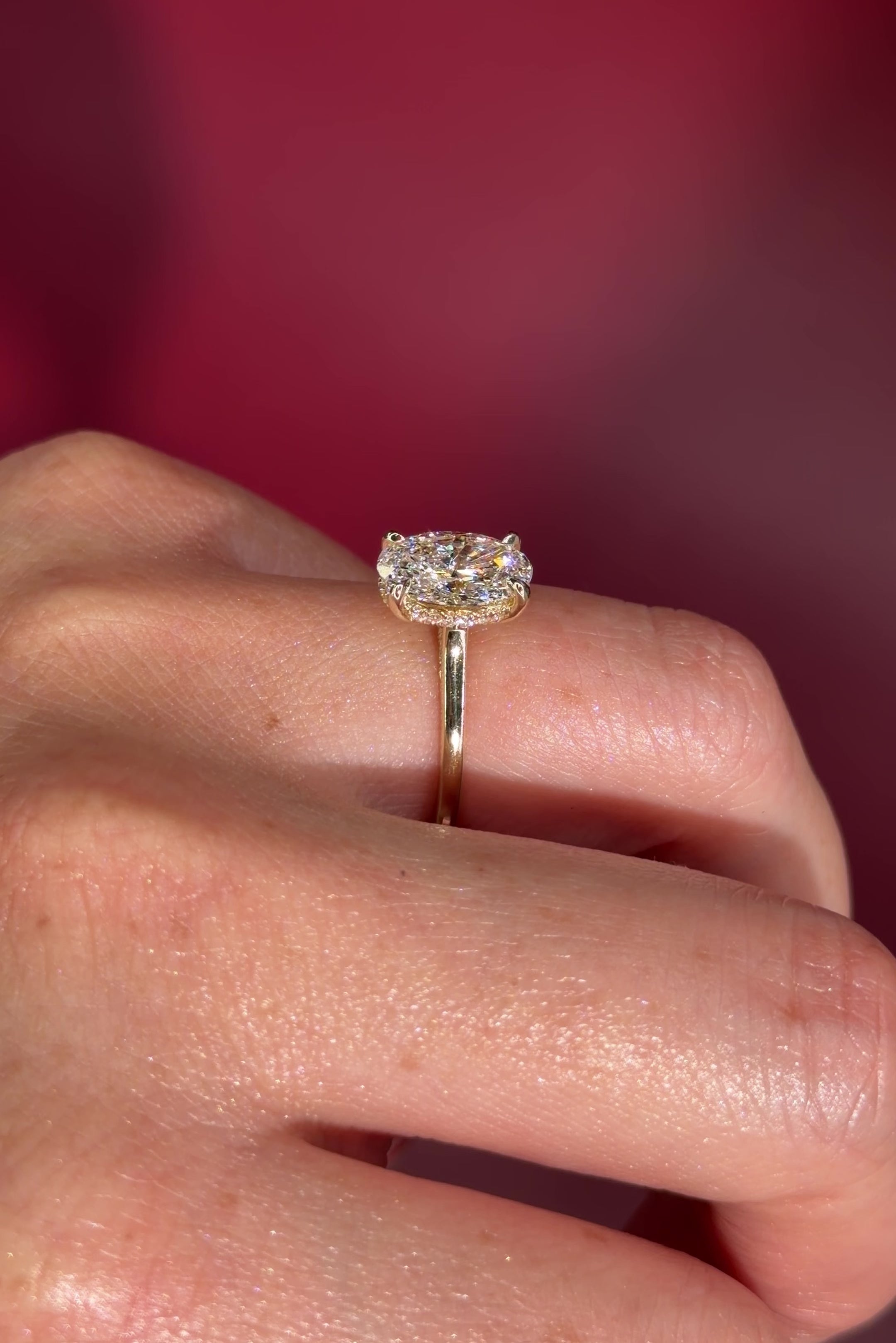 Oval solitaire with hidden halo and diamond bridge in yellow gold