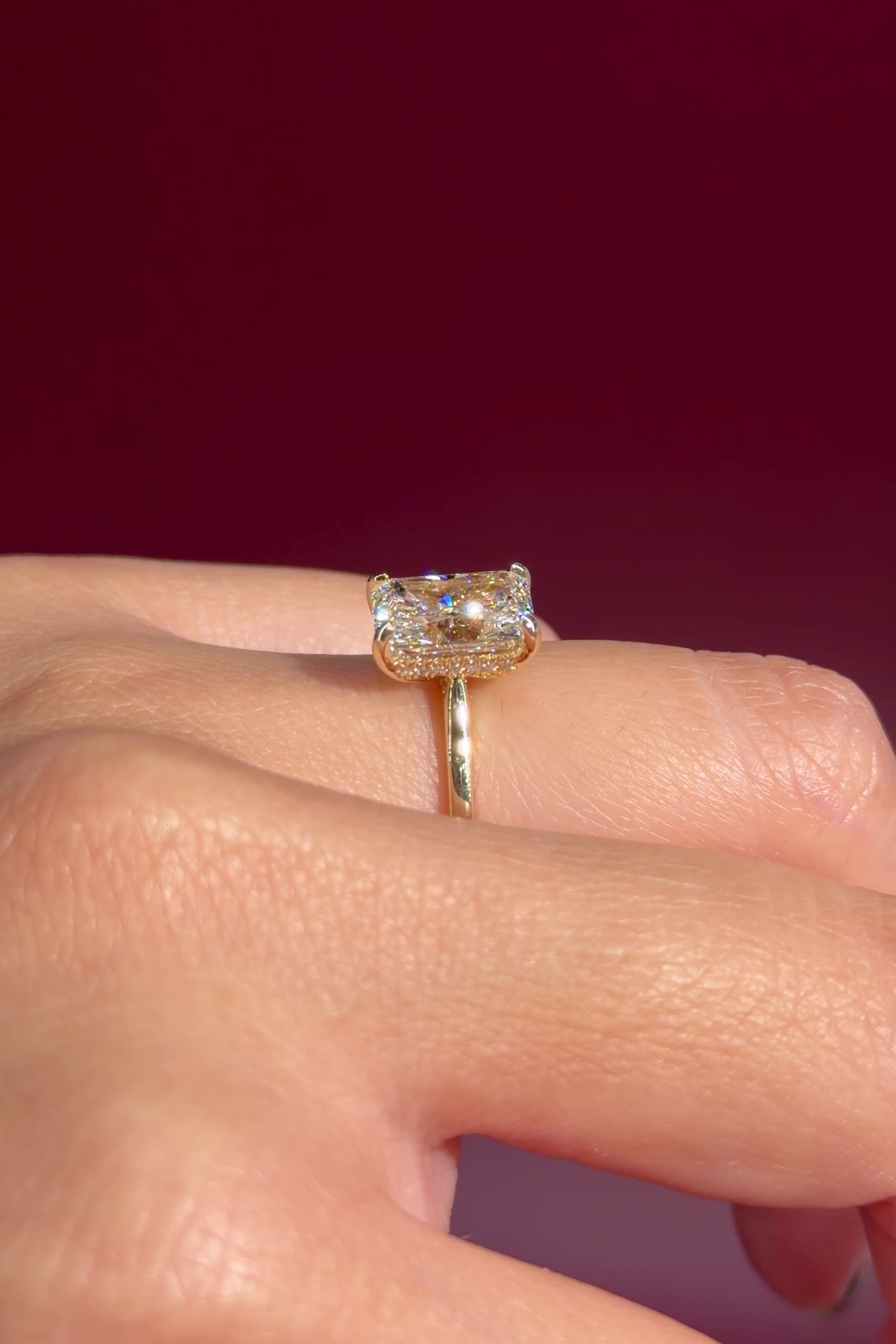 radiant lab diamond yellow gold solitaire engagement ring cathedral setting with diamond bridge on hand