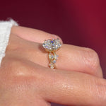 oval lab diamond cluster side stones whimsical yellow gold engagement ring on hand