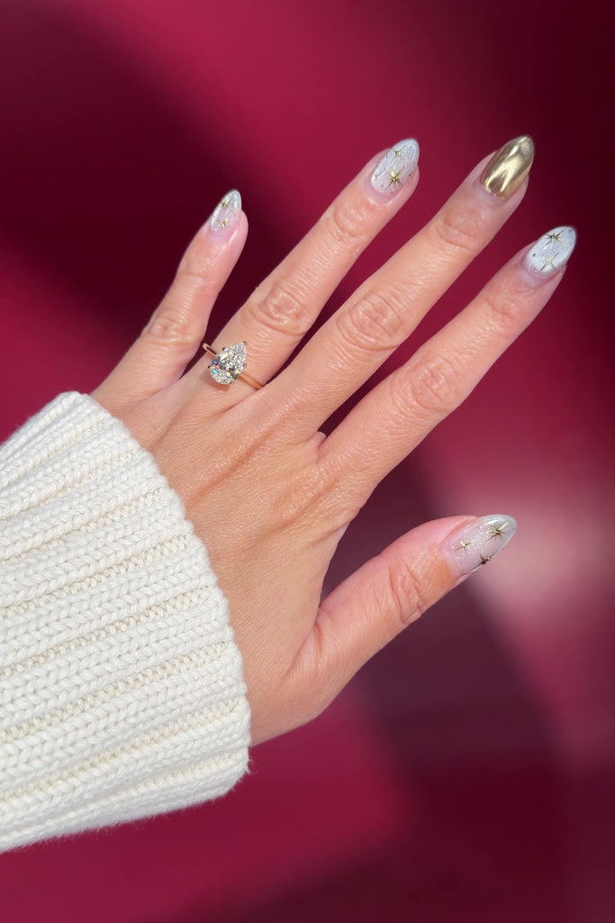 pear lab diamond solitaire engagement ring with cathedral and belt on hand