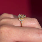 2.01ct F-VVS2 Pear Lab Diamond Sarah. The Sarah features a tapered high polish comfort fit band with a trio of diamonds. The trio features two marquises and one round diamond. The baskets are all lifted to fit a straight band flush against the body.