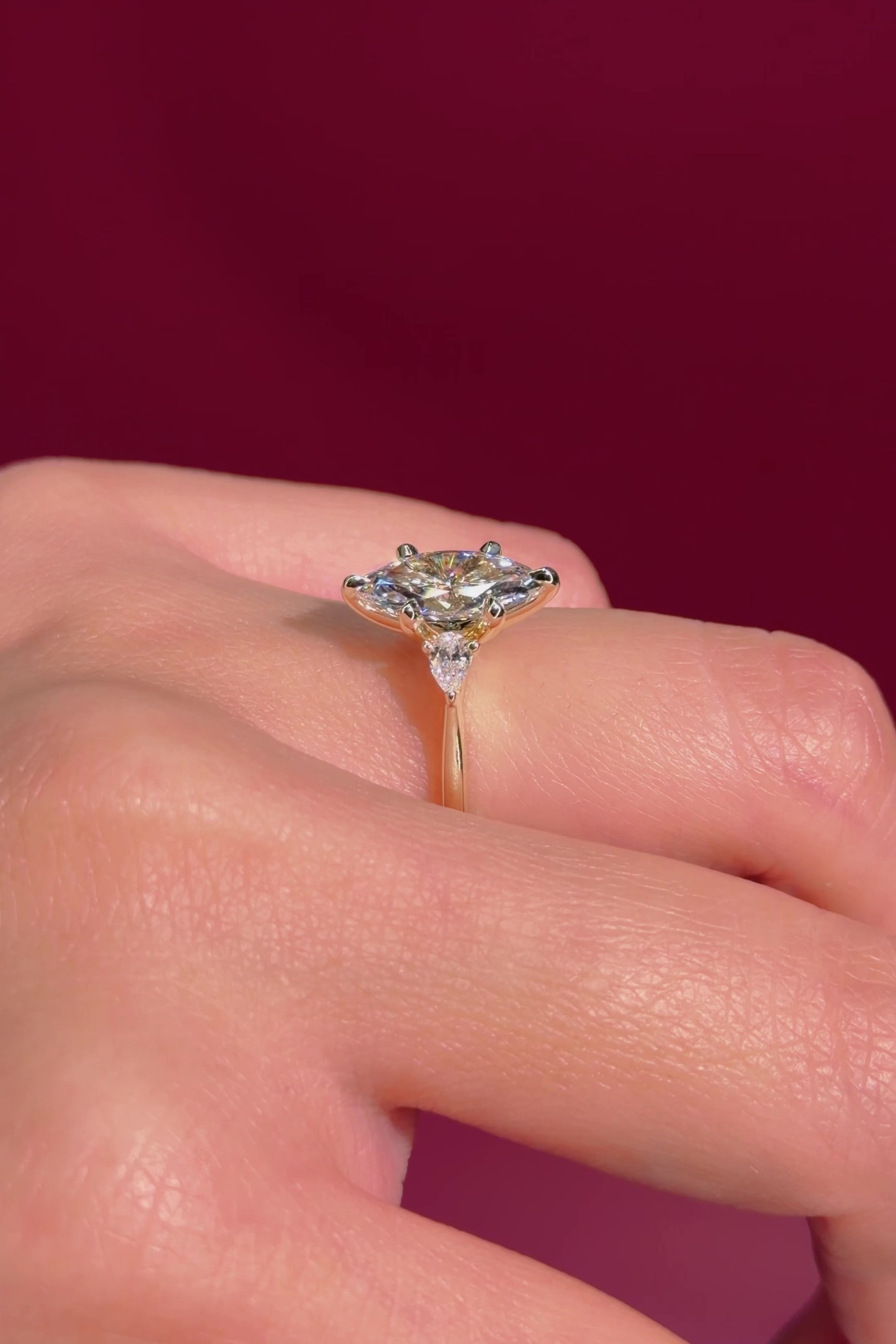 marquise yellow gold engagement ring with pear side stones on hand