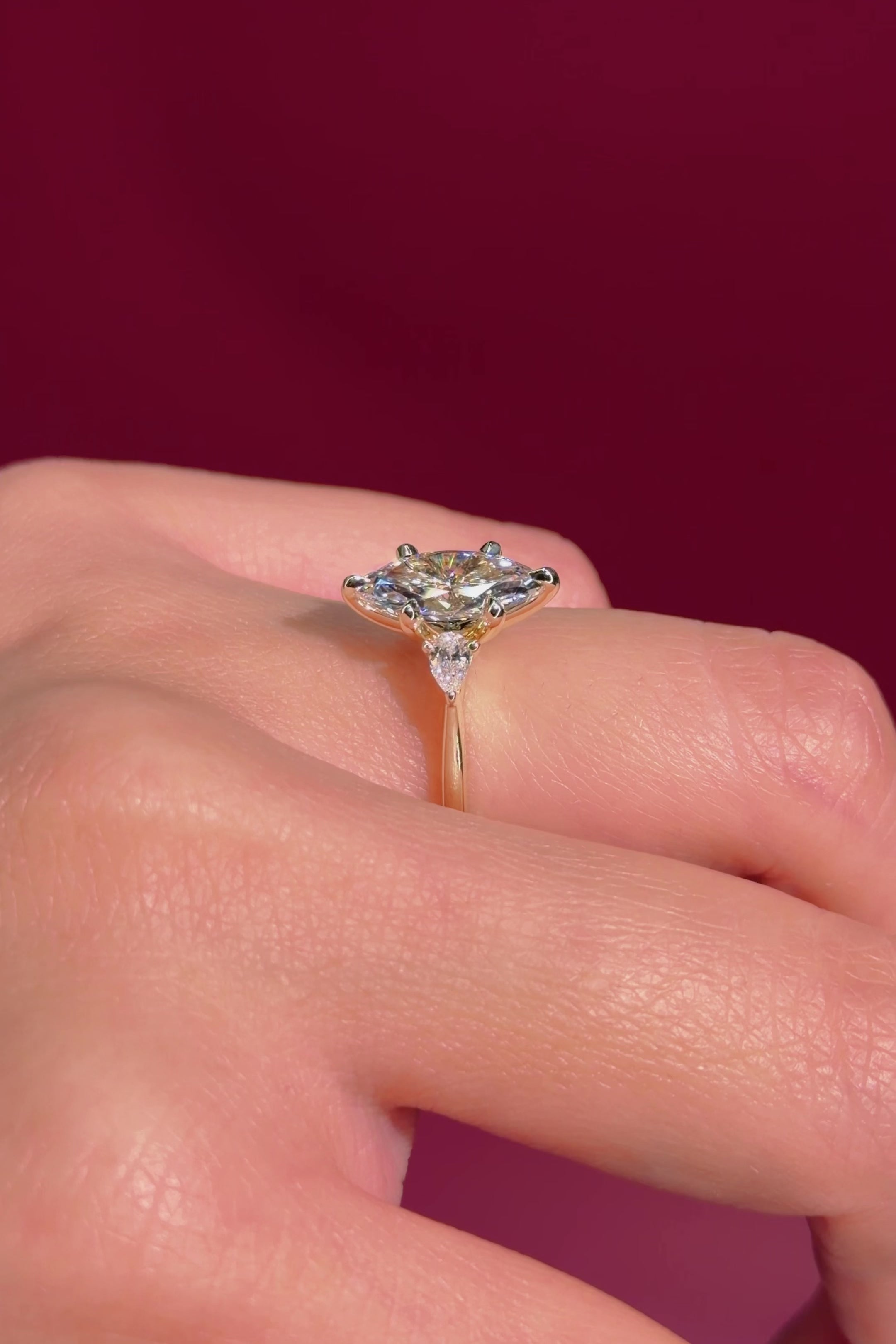 marquise yellow gold engagement ring with pear side stones on hand