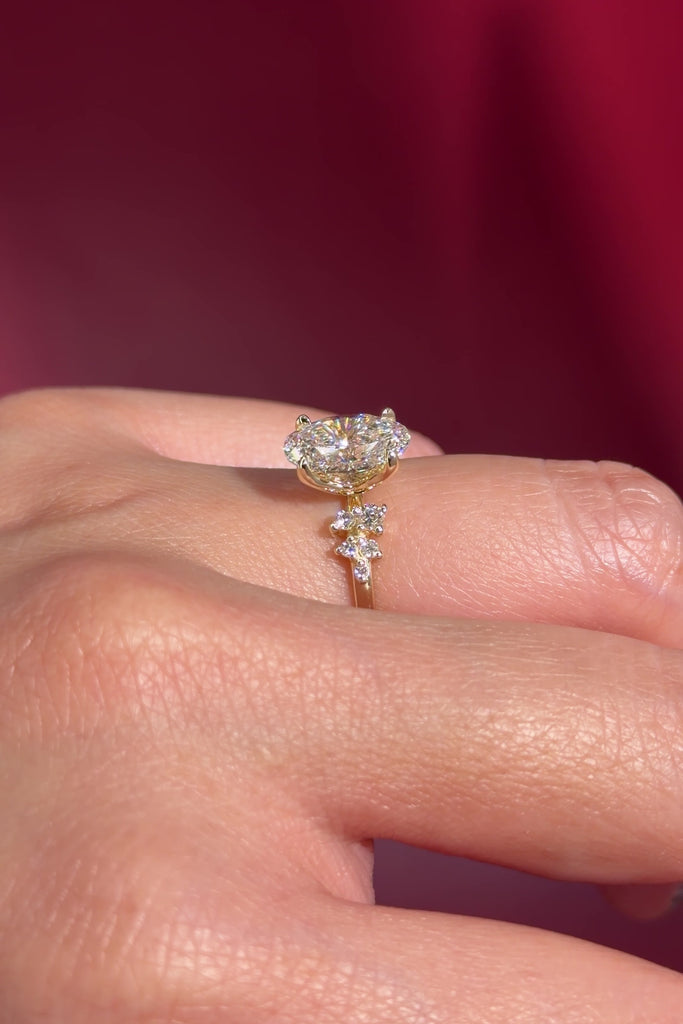 oval lab diamond engagement ring side stone cluster nature inspired yellow gold setting with petal prong basket on hand