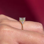 emerald lab diamond engagement ring trio side stone cluster yellow gold on hand