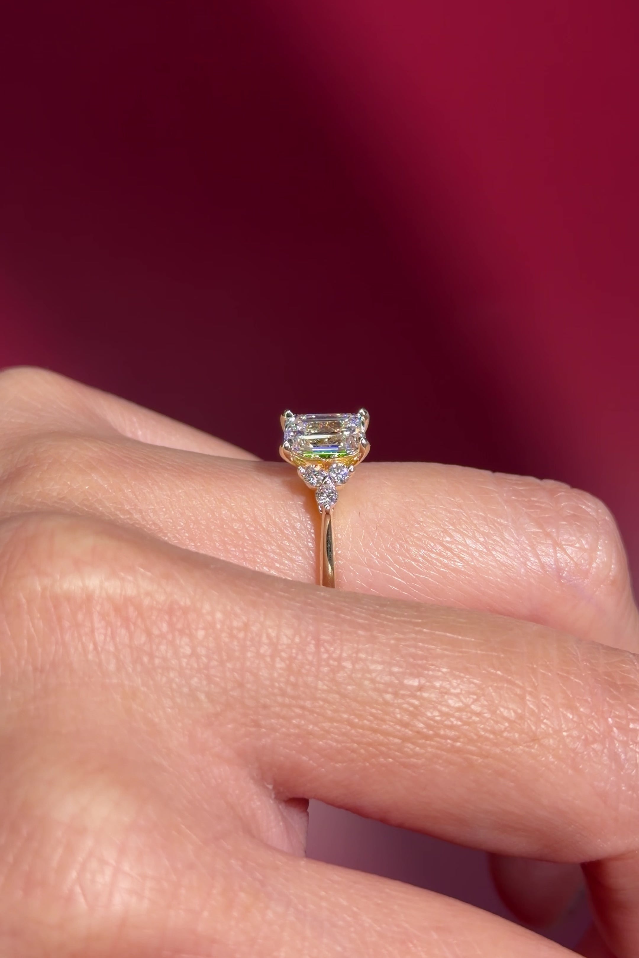 emerald lab diamond engagement ring trio side stone cluster yellow gold on hand